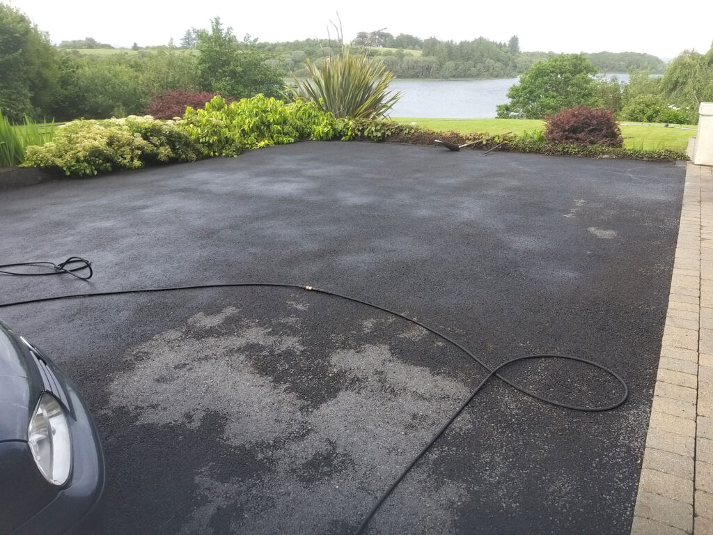 Freshly Laid Black Asphalt Driveway with A Coiled Garden Hose — Alpha and Omega Refurbishment in Tuam, Galway
